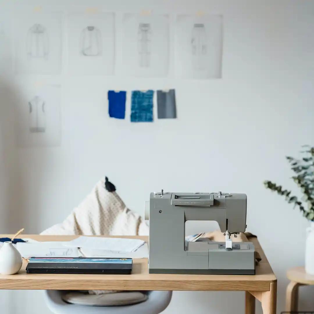 A photo of a table with a sewing machine and patterns on the wall